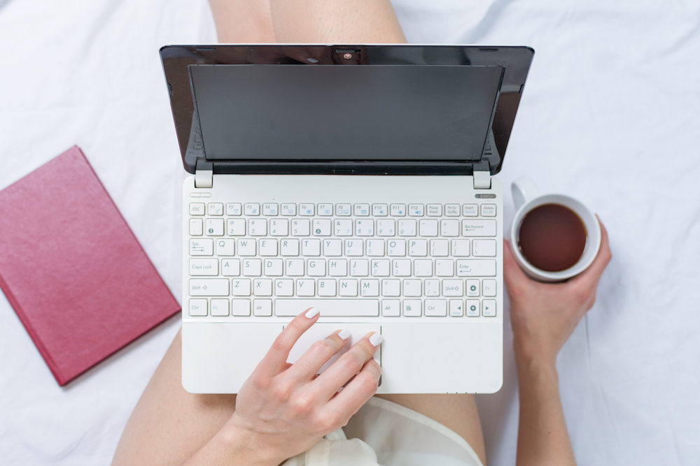 Woman working on a notebook while in bed